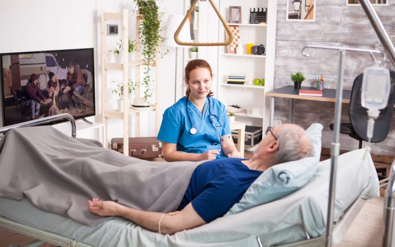 Female doctor with stethoscope sharing comfort to old man in nursing home.